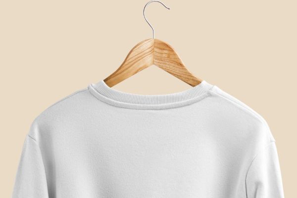Camiseta branca pendurada em um cabide de madeira.