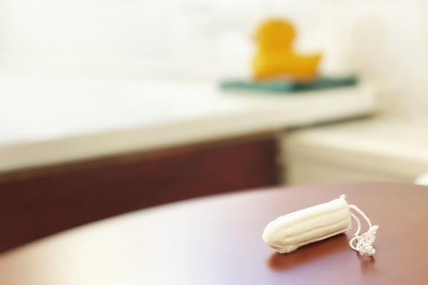 A tampon on a table with a bathtub and a rubber duck blurred in the background.