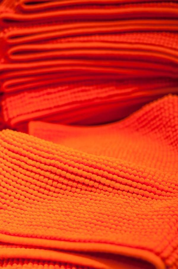 Stack of folded orange microfiber cleaning cloths.