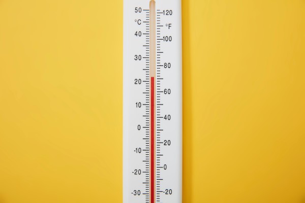 A thermometer against a yellow background.