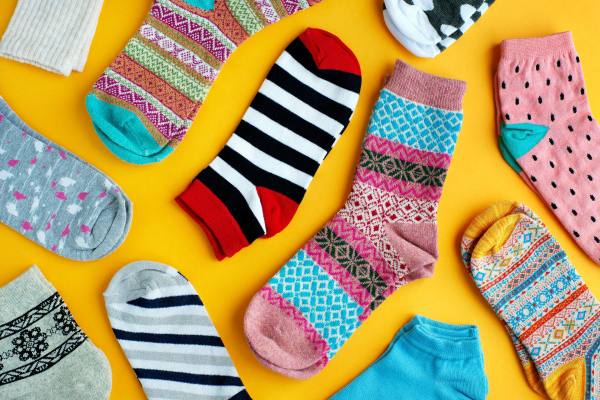 Assorted colourful socks laid out on a yellow background.