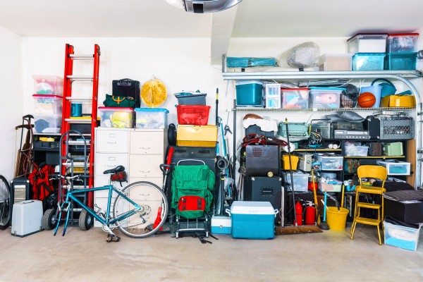 A cluttered garage with assorted items, including bicycles, storage boxes, tools, and sports equipment.