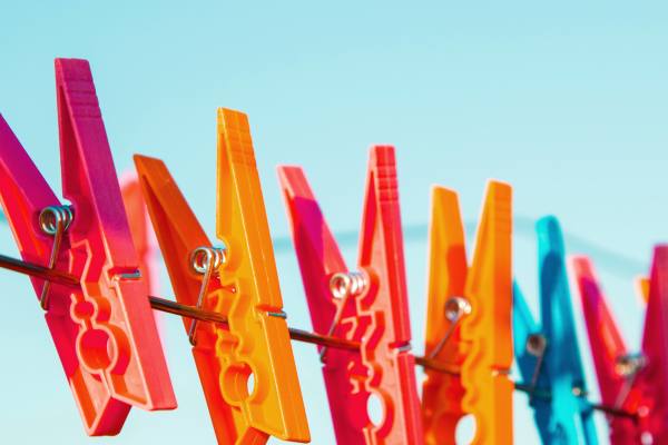 Colourful plastic clothes pegs on a washing line against a blue sky.