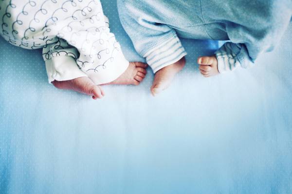 A baby's feet peeking out from a blue blanket and white patterned clothing.