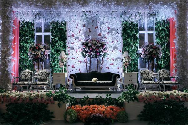 Dekorasi panggung dengan sofa elegan dan bunga untuk acara pernikahan.