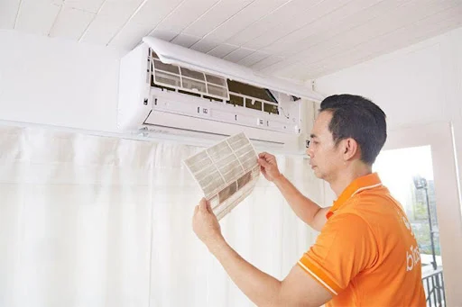 Người đàn ông đang làm sạch bộ lọc của máy điều hoà không khí.