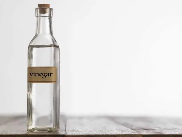 Chai giấm trong suốt có nắp gỗ và nhãn 'vinegar'.