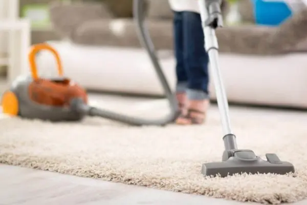 Người dùng máy hút bụi để làm sạch thảm.