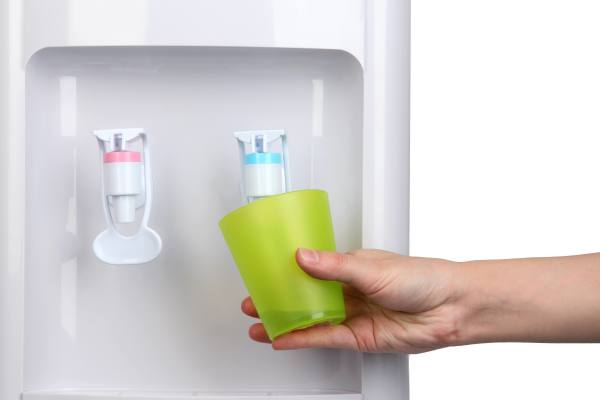 Tay đang đặt một chai màu xanh lá vào trong ngăn cửa tủ lạnh.