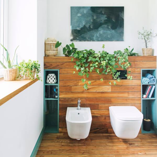 Modern bathroom interior with wooden walls, a bidet, toilet, and indoor plants.