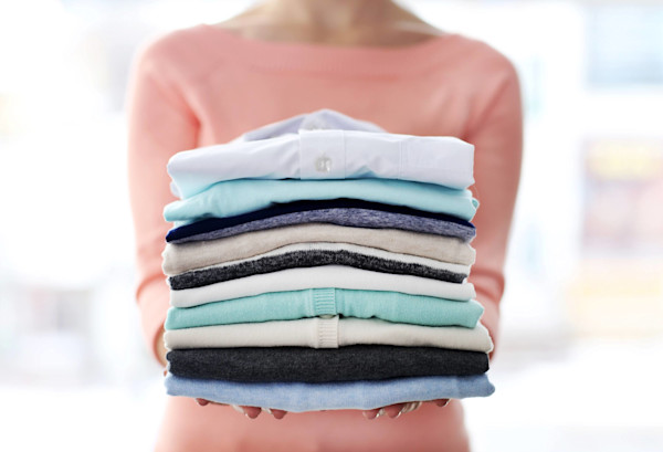 Una persona sosteniendo un montón de ropa doblada.