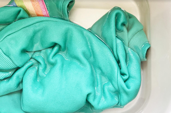 Una prenda de vestir verde turquesa en una pileta para lavar ropa.
