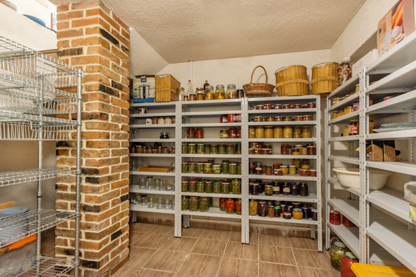 A well-organized pantry with shelves of canned goods and baskets.