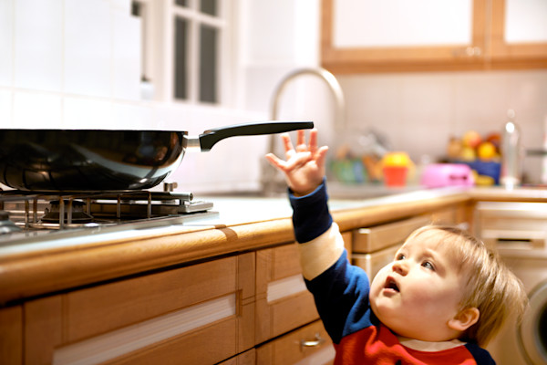 Niño pequeño alcanzando una sartén en la cocina.