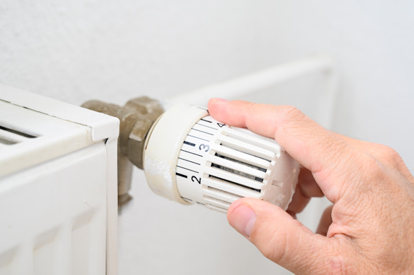 Mano ajustando el termostato de un radiador.