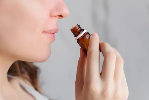 Seorang wanita mencium aroma dari botol kecil.