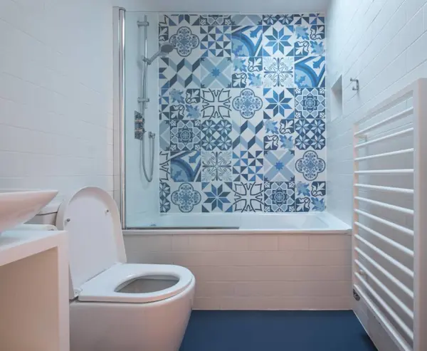 Kamar mandi dengan dinding bermotif ubin, shower, toilet, dan pemanas handuk.
