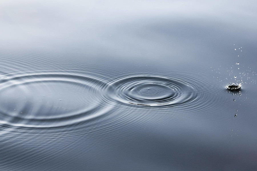 Wasser mit konzentrischen Kreisen und aufspritzenden Tropfen.