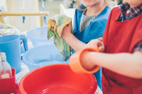 Children engaged in cleaning activity with cloths and buckets.