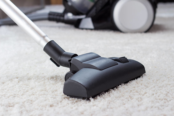 Vacuum cleaner nozzle on a shaggy carpet with the vacuum body in the background.