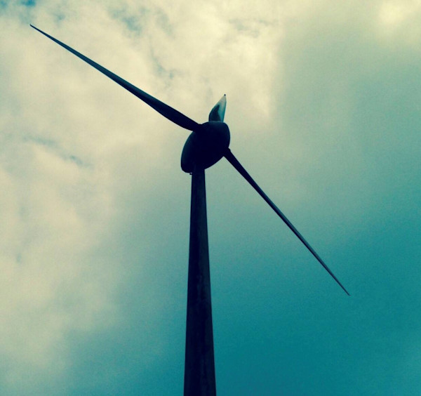 Silueta de un aerogenerador contra el cielo nublado.