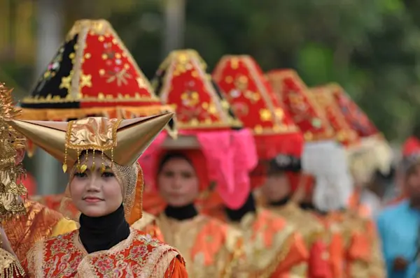 Beberapa orang mengenakan pakaian adat dalam suatu parade.
