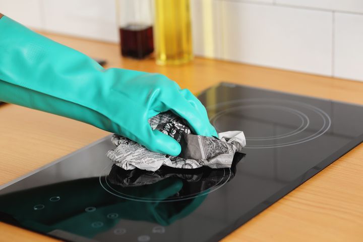 Step 4: Person using newspaper to clean hob 