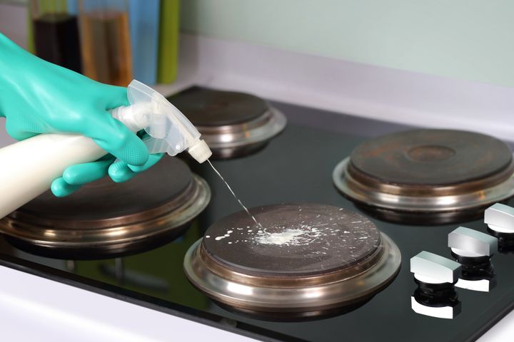 Step 2: person spraying cleaning fluid on electric hob