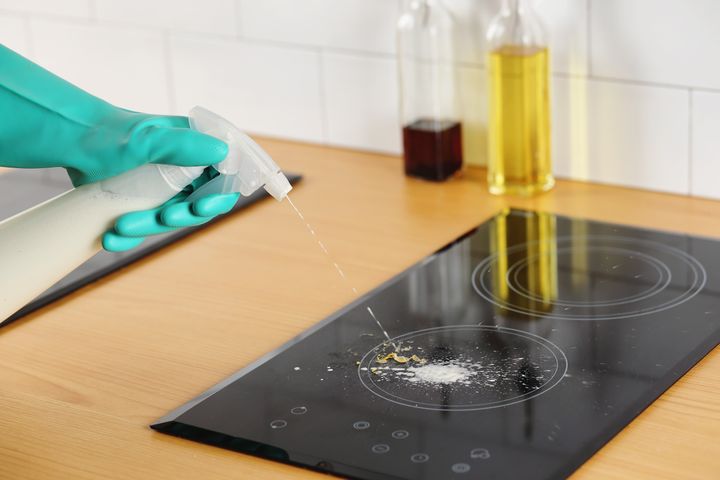 Step 2: Person spraying cleaning fluid onto hob 